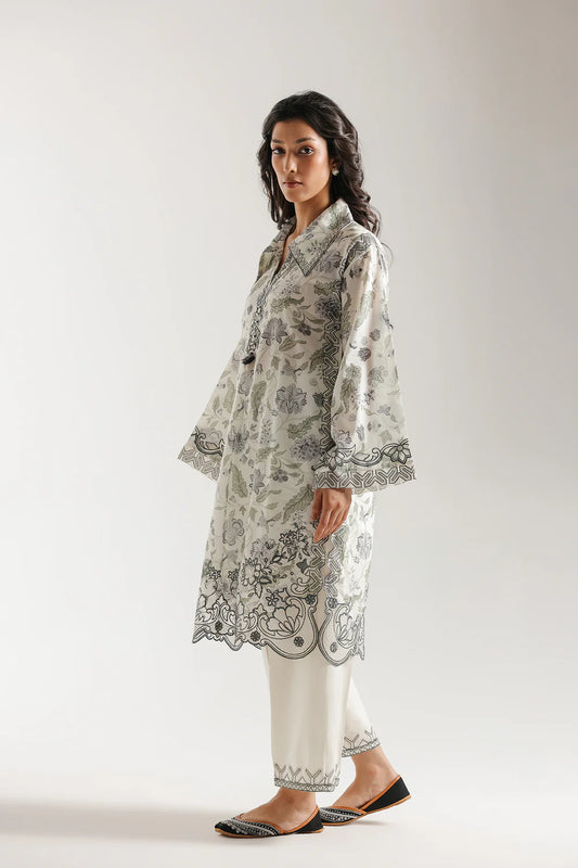 Woman wearing a white and black patterned kurta with pants on a plain background