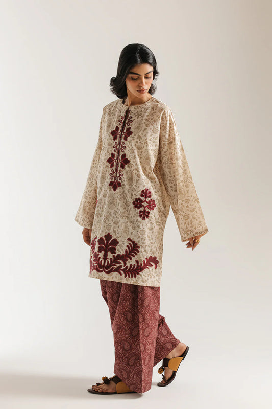 Woman wearing a patterned beige and red outfit on a white background