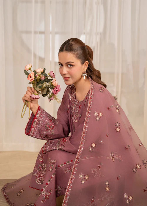 Woman in a traditional outfit holding flowers against a white curtain background