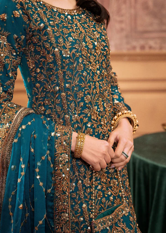 Teal embroidered traditional outfit with gold details on a blurred background