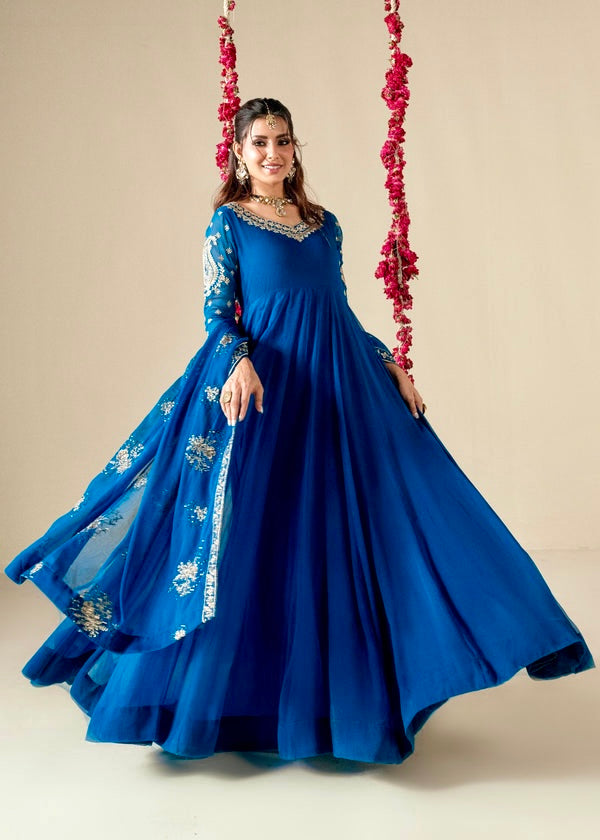 Woman in a blue gown with white embroidery on a beige background