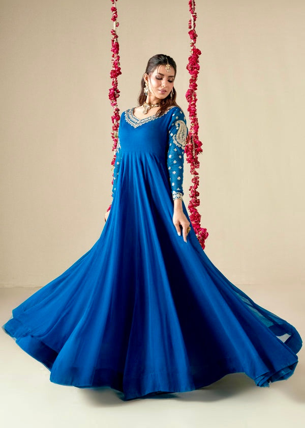Woman in a blue gown with floral decorations on a swing against a beige background