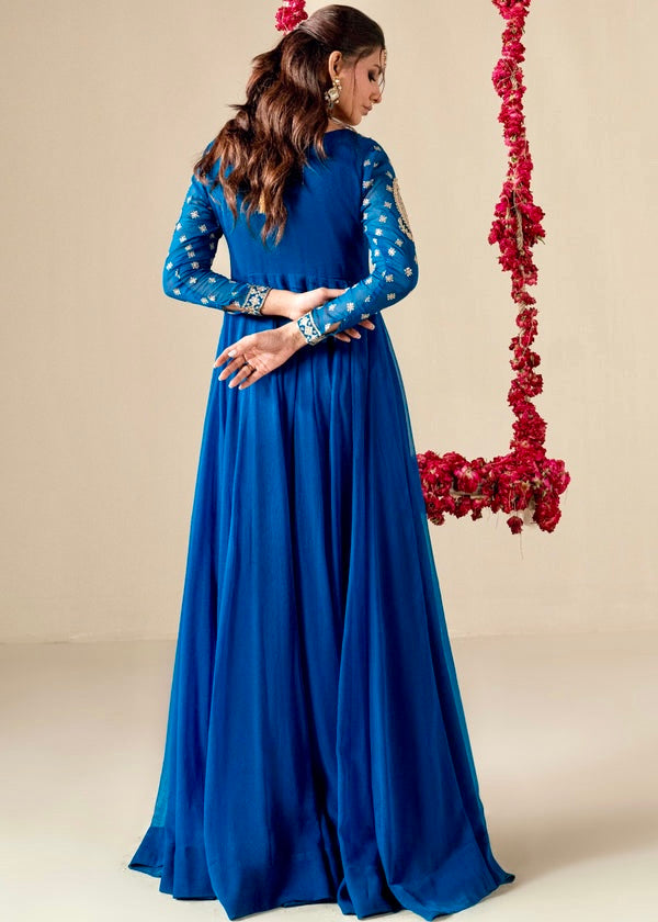 Woman in a blue dress standing next to a decorative swing with red flowers on a beige background