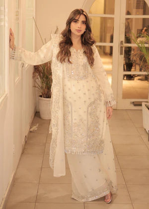 Woman in a white embroidered traditional outfit standing in a well-lit room.