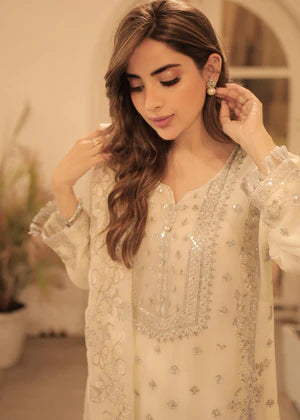 Woman adjusting earrings in a softly lit indoor setting