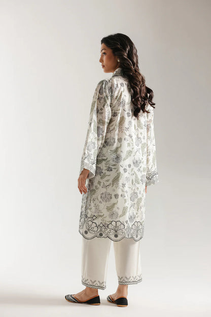 Woman wearing a floral embroidered kurta with white pants on a plain background