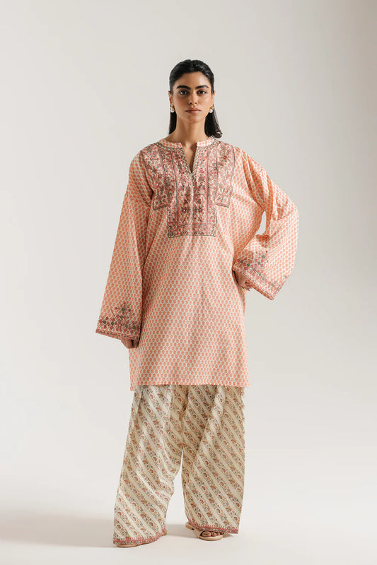 Woman wearing a pink patterned kurta with beige pants on a white background
