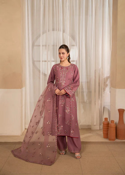 Woman in a mauve traditional outfit with a sheer dupatta in a room with beige walls and decorative vases.