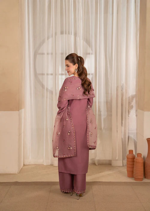 Woman in a pink traditional outfit standing in a room with decorative elements.