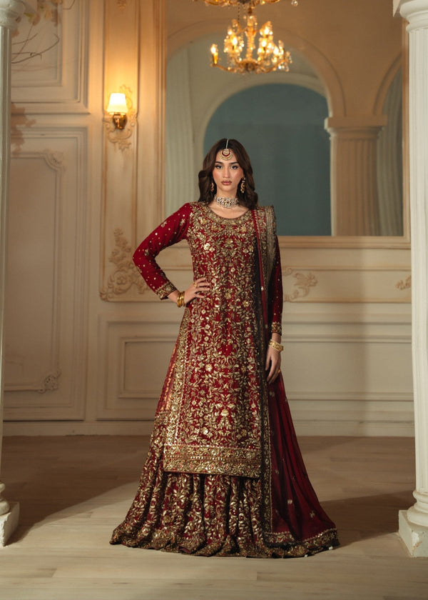 Woman in a traditional embroidered outfit standing in an ornate room with chandelier.