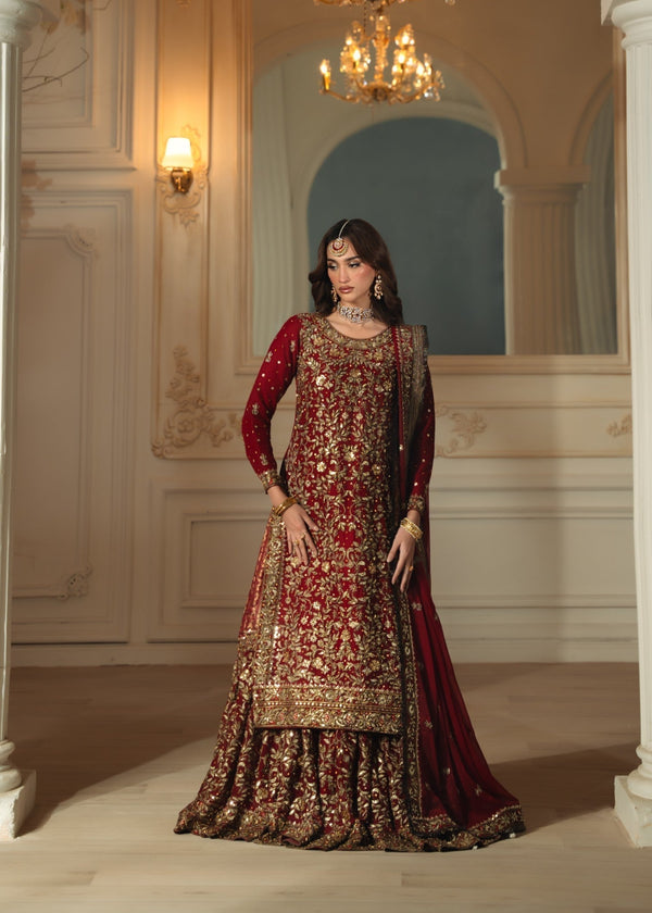 Woman in a traditional embroidered outfit standing in an elegant interior setting.