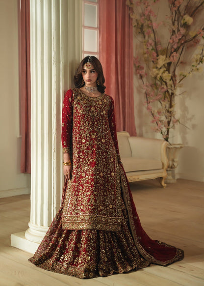 Woman in a traditional embroidered dress standing in an elegant room with decorative elements.