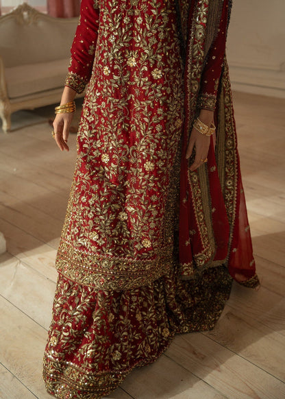Red and gold embroidered traditional outfit on a wooden floor.