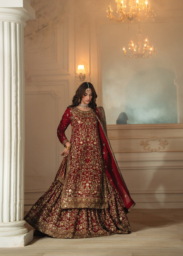 Woman in a traditional embroidered outfit standing in an elegant room with chandeliers.
