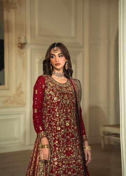 Woman in a red and gold traditional outfit with jewelry in an elegant room.