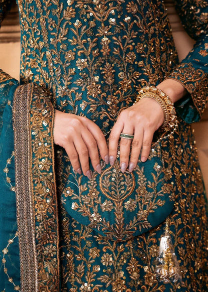 Close-up of a person wearing a teal and gold embroidered traditional outfit with jewelry.